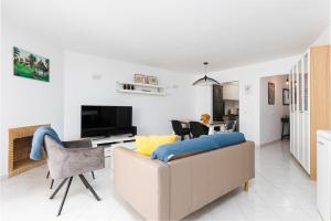 a white living room with a couch and a tv at Apartment Estrelícia Direct beach access in Porches