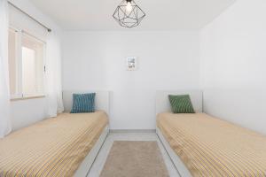 two beds in the corner of a room at Apartment Estrelícia Direct beach access in Porches +17 photos