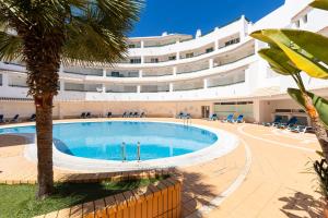 a swimming pool in front of a large building at Apartment Estrelícia Direct beach access in Porches