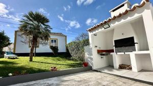 a white house with a palm tree in the yard at Retiro dos Biscoitos in Biscoitos