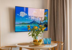 a tv hanging on a wall with a table with flowers at Apartamenty Boszkowo Aquarius Blue in Boszkowo +56 photos