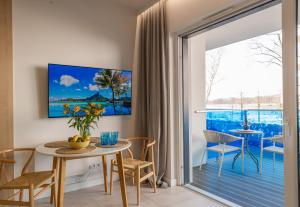 a living room with a table and chairs and a sliding glass door at Apartamenty Boszkowo Aquarius Blue in Boszkowo