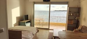 een slaapkamer met een balkon met uitzicht op de oceaan bij Appartement pieds dans l eau in Ajaccio