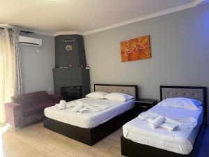 a hotel room with two beds and a chair at Villa AlMar in Sarandë