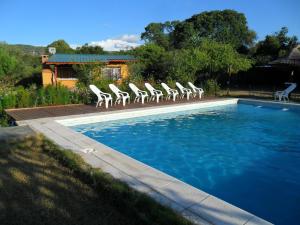 Un grupo de sillas junto a una piscina. en Cabañas Mandala, en San Marcos Sierras