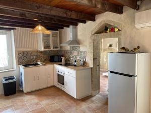 a kitchen with white cabinets and a white refrigerator at Maison de village atypique in Issirac
