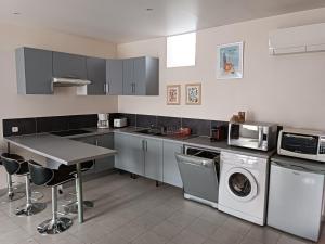 a kitchen with a table and washing machines and a microwave at Duplex dans belle propriété avec piscine in Les Essarts-le-Roi