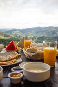 a table topped with plates of food and glasses of orange juice at Nosara Hideaway 1 - Mountain View Cabins in Naranjal