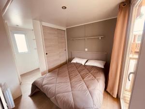 a bedroom with a bed in a room with a window at Mobil Home Bouginvilliers 3 in Valras-Plage