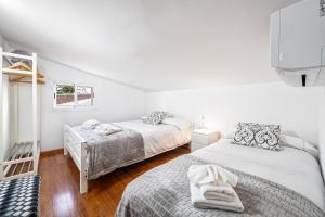 Habitación con 2 camas, paredes blancas y suelo de madera. en Privé Paradise, en Maspalomas