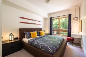 a bedroom with a bed with yellow pillows and a window at Tremblant Prestige - Étoile 1500-2 in Mont-Tremblant