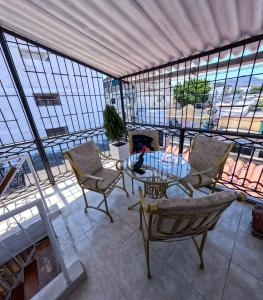 een woonkamer met stoelen en een tafel en ramen bij Hostal El Amanecer Costero in Santa Marta