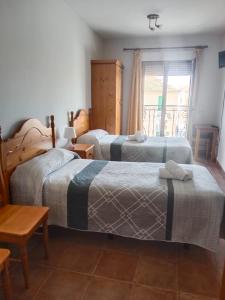a hotel room with two beds and a window at Hostal Restaurante Bar Conrad in Abades