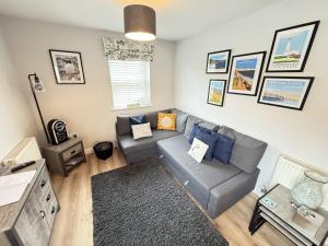 a living room with a gray couch and blue pillows at The Puffin Pad - Part of the The Bay Filey Holiday Village with pool, gym and direct beach access, pub, restaurant, tennis and meadows walks in Filey