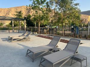 马斯喀特Muscat bay Zaha 2 bedroom的一排躺椅和一张野餐桌 更多11张照片