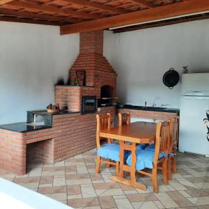 a kitchen with a wooden table and a brick oven at Chácara Pedacinho do Céu in Socorro