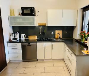 a kitchen with white cabinets and a sink and a microwave at Domek całoroczny in Swornegacie