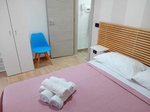 una camera da letto con asciugamani su un letto con una sedia blu di B&B EmaNik a Gioia Tauro