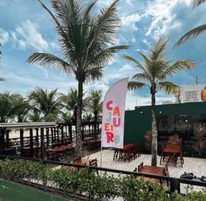 un restaurante con palmeras y un cartel de tabla de surf en Apto com 1 dormitorio proximo a praia, en Praia Grande