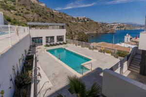 a house with a swimming pool next to a mountain at RentitSpain Playa, piscina y terraza al mar in La Herradura