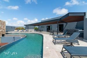 a swimming pool with chairs and tables and a building at Modern 1 Bedroom Apartment with Luxury Amenities at Paramar Black by Waves in Tulum