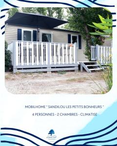 a house with a white fence and an umbrella at Sandilou lesPetitsBonheurs 2 Chambres Climatisé TV in Sigean