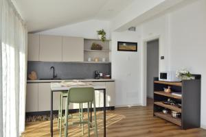 a kitchen with white cabinets and a table and chairs at ALMA Guest House in Pieve di Soligo