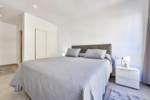 a white bedroom with a large bed and a night stand at Flat 58 - City Center Moraira in Moraira