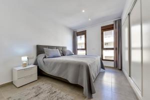 a white bedroom with a bed and a night stand at Flat 58 - City Center Moraira in Moraira