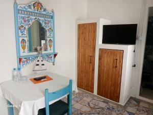 a room with a table and a television on a wall at Dar Evelyne in Mahdia