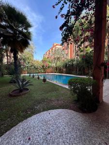 a swimming pool in a garden with a palm tree at MELBARI Central-Appart in Marrakech