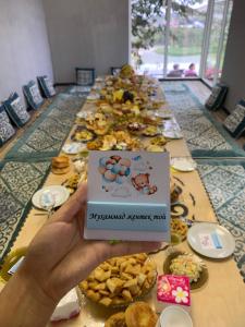 a person holding up a sign in front of a table of food at Панорама in Bishkek