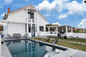a white house with a swimming pool in front of it at Villa Sunset Albatross in Nea Potidaea