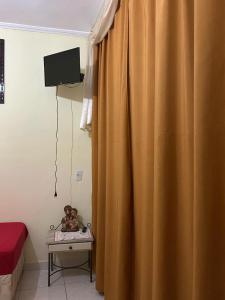 une chambre avec un rideau et un lit bébé avec une télévision dans l'établissement Pousada Bom Pastor, à Cachoeira Paulista