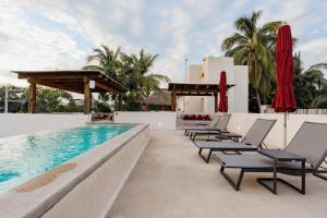 ein Pool im Resort mit Liegestühlen und Sonnenschirmen in der Unterkunft Casa Mava in Puerto Escondido