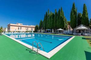 a large swimming pool with a green floor and trees at TatyHouse in Rome