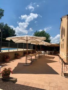 un patio con mesas, sombrillas y una piscina en Agriturismo Cerquatonda, en Montalto delle Marche