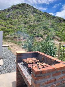 a brick grill with meat and a mountain in the background at Las Casitas CAFAYATE in Cafayate