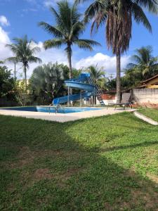 a swimming pool with palm trees in the background at Pousada Sunset Itaúna in Saquarema
