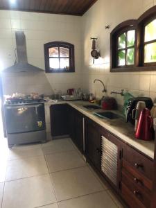 a kitchen with a sink and a stove top oven at Pousada Sunset Itaúna in Saquarema