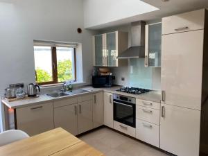 a kitchen with white cabinets and a stove top oven at Beach House Inch in Inch