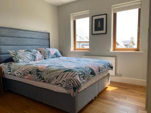 a bed in a bedroom with two windows at Beach House Inch in Inch +3 photos
