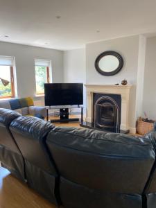 a living room with a leather couch and a television at Beach House Inch in Inch