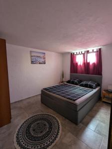 a bedroom with a large bed with red curtains at Apartman Slavica in Gornji Karin