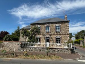 an old brick house with a white fence on the street at Proche plage, maison de bourg pleine de charme in Gouville-sur-Mer