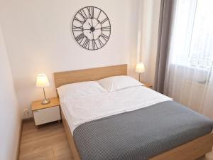 Un dormitorio con una cama con un reloj en la pared. en Grand Apartament - prywatny parking, blisko Szpital Arkońska, en Szczecin 14 fotos más