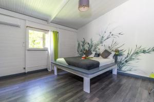 a bedroom with a bed with a painting on the wall at Bel'Eden Résidence Le Coin de L'Artiste in Le François