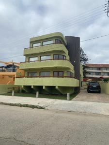 a green building with a car parked in front of it at "Marenostro" Dpto #3, departamento frente al mar in Algarrobo