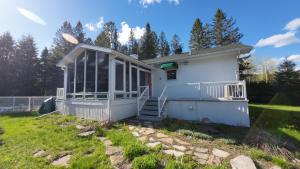 a white house with a porch and stairs in a yard at Cottage with inground pool outside in Saint-Damien