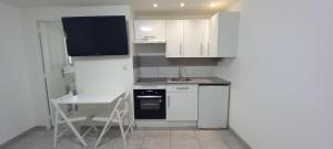 a kitchen with white cabinets and a table and a sink at Studio centre ville de Gagny in Gagny